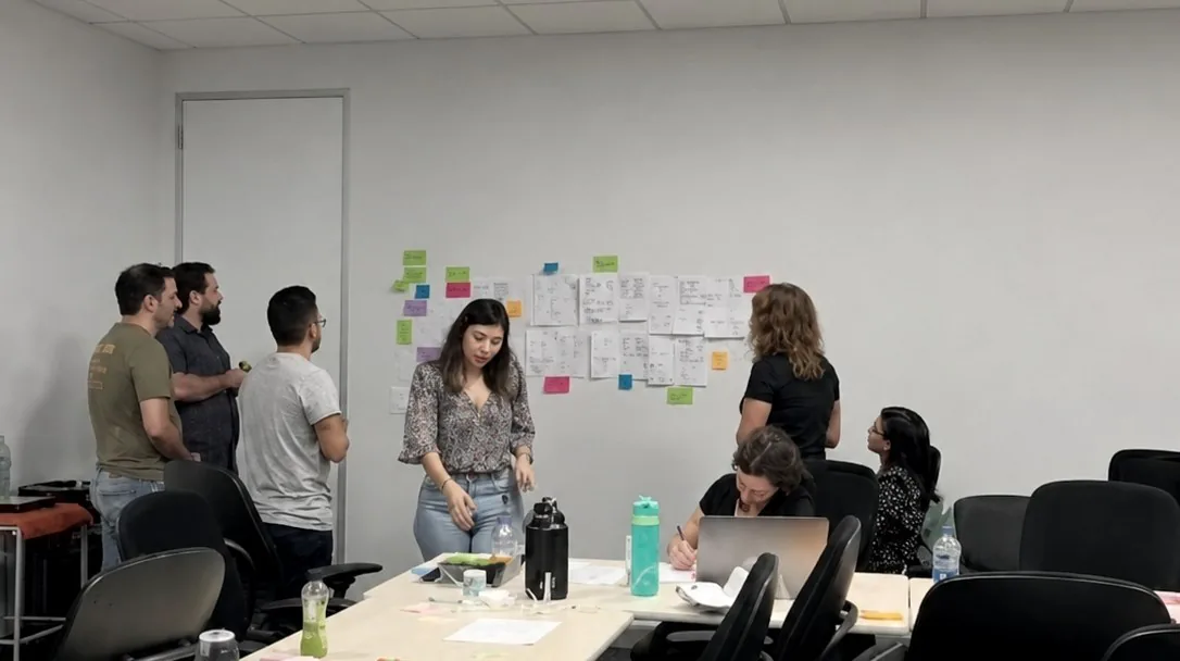Ana Rosa facilitating a workshop in front of a wall of sketches and sticky notes